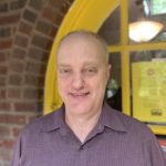 Photo of Steve Cleaver in a maroon shirt in front of a yellow door